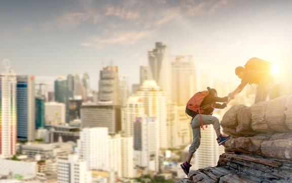 Asia Couple Hiking Help Each Other In Mountains With Sunlight And City Background.