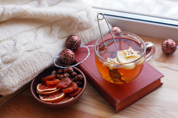 Cup of tea, snacks, book and warm blanket on windowsill, close up, relax unplug background, seasonal homely weekend, love to read concept