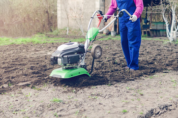 Fototapeta na wymiar Young girl working in a spring garden with a cultivator