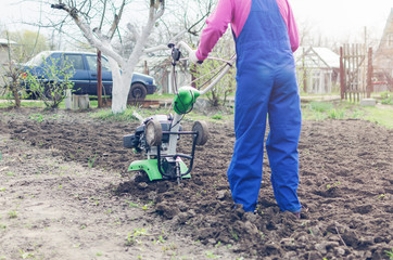 Young girl working in a spring garden with a cultivator