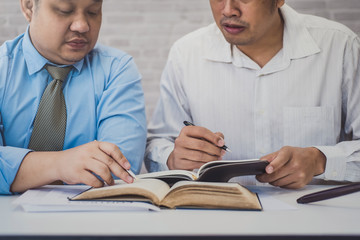 Fototapeta premium Male lawyer teaching new lawyer and discussing with contract papers and wooden gavel on tabel in courtroom. justice and law ,attorney, court judge, concept.