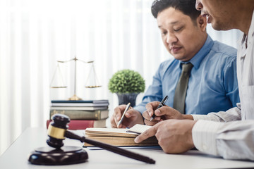 Male lawyer teaching new lawyer and  discussing with contract papers and wooden gavel on tabel in courtroom. justice and law ,attorney, court judge, concept.