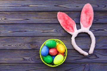 Carnival hare ears, Easter eggs in a basket on the background of a wooden table.