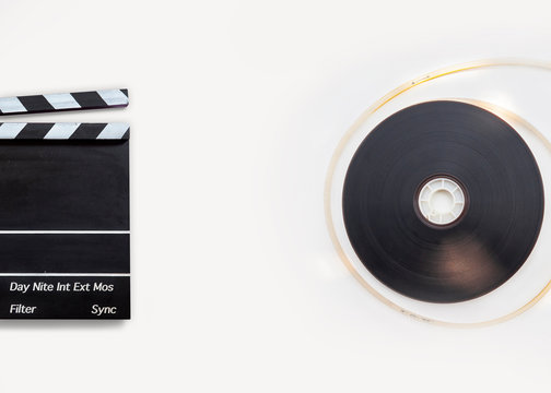 Movie clapper board and 8mm film reel on white background