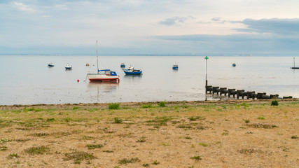 Fototapeta na wymiar Boats at low tide on the shore of the River Thames, seen in Southend-on-Sea, Essex, England, UK