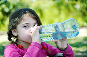 Cute little girl drinking fresh water from plastic bottle