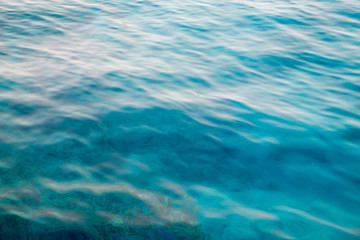 Fototapeta na wymiar Blue clear water. Beautiful blue sea wave photograph close up. Beach vacation at sea or ocean. Background to insert images and text. Tourism, travel.