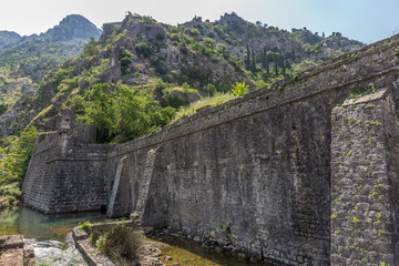 Fototapeta na wymiar Fortification Wall Of Adriatic ancient Town Kotor in Montenegro. Castle walls and river