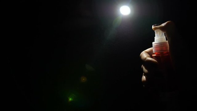 spray woman's hand on black background in dark