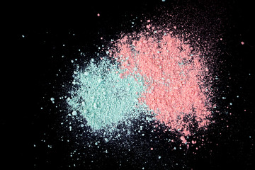 Pile of natural colored pigment powder. Green pink  powder particles splatter on black blackground.