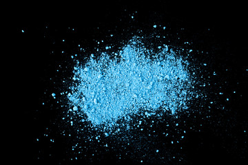 Pile of natural colored pigment powder. Blue powder particles splatter on black blackground.