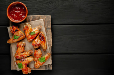 Grilled chicken wings in a barbecue sauce with parsley on a cutting board on a concrete table. Top view with copy sp