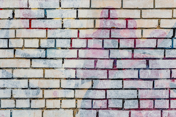 Beautiful horizontal texture of part of an old crashed brick colored wall in yellow red blue green brown hue on the photo