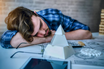 Engineering man working overwork and sleep on the desk with blueprint mechanical parts in office. having a bad stress and overwork concept - Image
