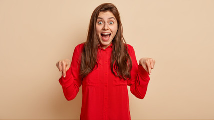 Horizontal shot of impressive European woman demonstrates nice shoes, wears red shirt, has...