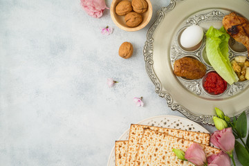 Jewish holiday Passover background with matzo, seder plate and spring flowers.