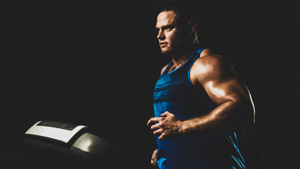 Fit muscular man in sportswear running on treadmill in modern gym, with color imitating social network filter