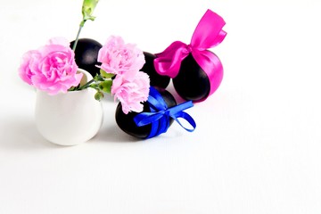 Obraz na płótnie Canvas black easter eggs and pink carnation flowers on a white background