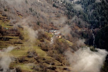 View  of a green village under clouds on a mountain 