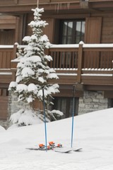 Pair of ski in front of a chalet with winter background 