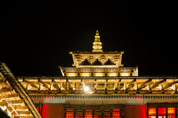 Tashichho Dzong at night, Thimphu, Bhutan. Towers topped by triple-tiered golden roofs.  The central Tower is called Utse.