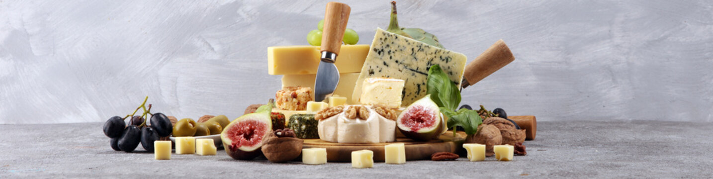 Cheese plate served with figs, various cheese on a platter on wood