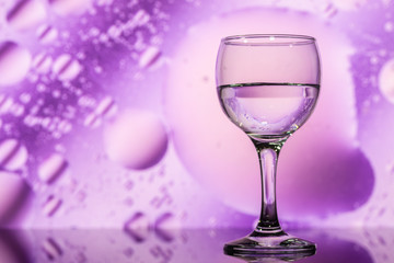 ransparent glasses with water with oily drops on colorful background 