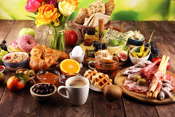 breakfast on table with bread buns, croissants, coffe and eggs