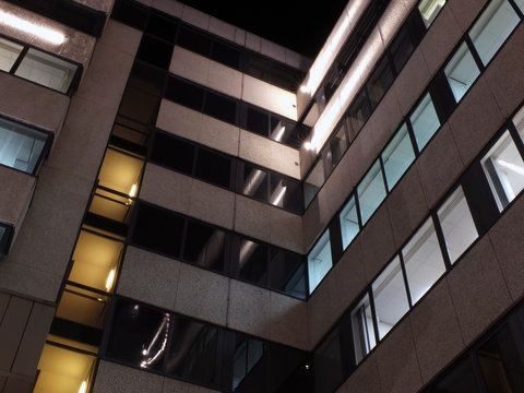 the corner of an office building at night with illuminated walls and lights shining on the exterior facade