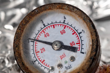 old rusty tire pressure gauge with red numbers on a white background