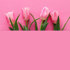 bouquet tulips over pastel pink wooden background. Top view
