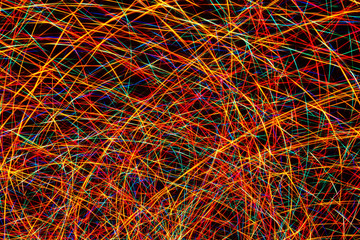 Colorful light painting abstract long exposure image with red, green, blue and yellow lines on a black background