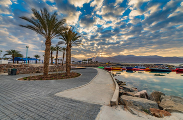 Fototapeta na wymiar Relaxing atmosphere on central public beach of Eilat - famous tourist resort and recreational city in Israel. Concept of healthy and happy vacation