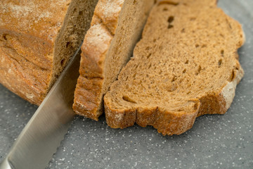 Sliced bread and knife on a gray background