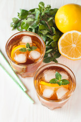 Refreshing citrus lemonade, summer drink. Ice tea with fresh lemon and mint on wooden background. Refreshment beverage concept.