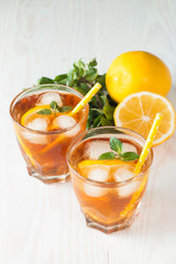 Refreshing citrus lemonade, summer drink. Ice tea with fresh lemon and mint on wooden background. Refreshment beverage concept.