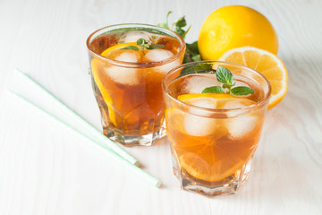 Refreshing citrus lemonade, summer drink. Ice tea with fresh lemon and mint on wooden background. Refreshment beverage concept.