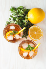 Refreshing citrus lemonade, summer drink. Ice tea with fresh lemon and mint on wooden background. Refreshment beverage concept.
