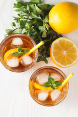 Refreshing citrus lemonade, summer drink. Ice tea with fresh lemon and mint on wooden background. Refreshment beverage concept.