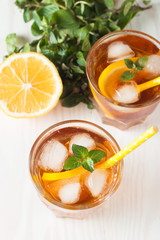 Refreshing citrus lemonade, summer drink. Ice tea with fresh lemon and mint on wooden background. Refreshment beverage concept.