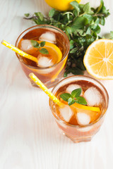 Refreshing citrus lemonade, summer drink. Ice tea with fresh lemon and mint on wooden background. Refreshment beverage concept.