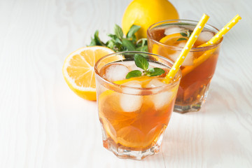 Fototapeta na wymiar Refreshing citrus lemonade, summer drink. Ice tea with fresh lemon and mint on wooden background. Refreshment beverage concept.