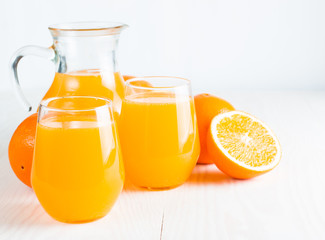 Close-up of a glass of orange juice with oranges fruits on wooden and stone background. Vitamins and minerals. Healthy drink and beverage concept.