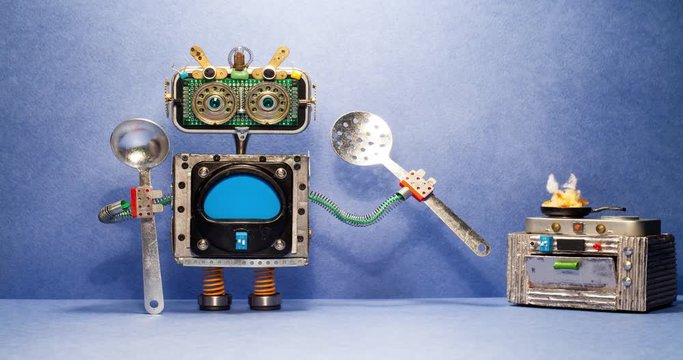 Chef robot cooking dinner. Funny robotic cook rotates skimmer, the appetizing dish is cooked on the stove. Creative design cyborg toy with kitchen utensils on blue background. Copy space.