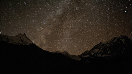Sky full of stars and Milky Way. Nightime scene with himalayan mountains and starry sky at in Nepal, Manaslu, Himalayas. Night landscape with bright milky way. Snowy mountains at night.