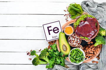 Food containing natural iron. Fe: Liver, avocado, broccoli, spinach, parsley, beans, nuts, on a...