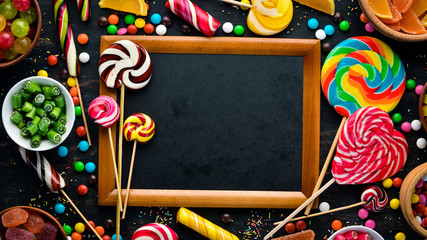 Background of colored candies and lollipops. Sweets. On a black background. Top view. free copying space.