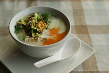Rice porridge with egg on a table.
