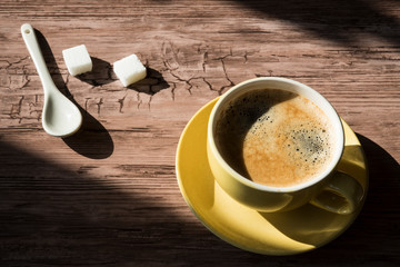 flat lay, close up, yellow cup and saucer, black coffee and sugar cubes in sunlight. with shadows, space for text