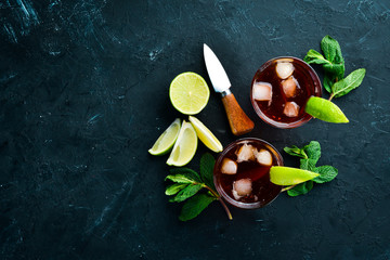 Alcoholic Beverage Rum, lime and mint on a black stone background. Top view. Free space for your...